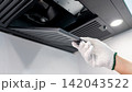 Male hand with protective gloves removing black range hood filter from cooker hood 142043522