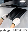 Male hand with protective gloves removing black range hood filter from cooker hood 142043524