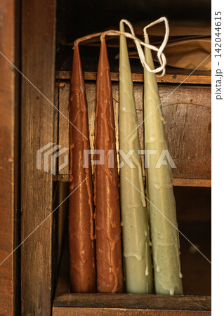 Handmade brown and green taper candles in vintage wooden cabinet drawer Handmade brown and green taper candles in vintage wooden cabinet drawer 142044615