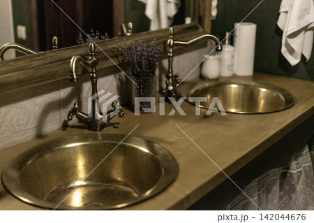 Vintage brass sinks with antique bronze faucets on wooden bathroom countertop Vintage brass sinks with antique bronze faucets on wooden bathroom countertop 142044676