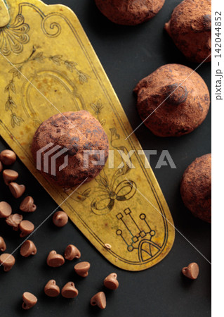 Chocolate truffles and vintage brass cake server on a black plate. 142044852