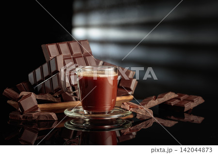 Mug of hot chocolate against broken bitter chocolate bars. Mug of hot chocolate against broken bitter chocolate bars. 142044873