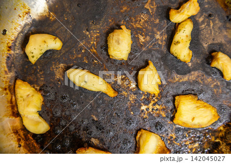 Burnt cooking oil with chicken breast pieces in stainless steel frying pan Burnt cooking oil with chicken breast pieces in stainless steel frying pan 142045027