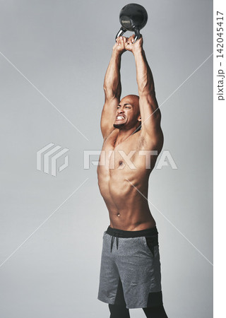 Black man, lift and kettlebell in studio shirtless and resilience for workout or training. Male person, athlete and weightlifting for muscle progress on gray background, tough and body challenge Black man, lift and kettlebell in studio shirtless and resilience for workout or training. Male person, athlete and weightlifting for muscle progress on gray background, tough and body challenge 142045417