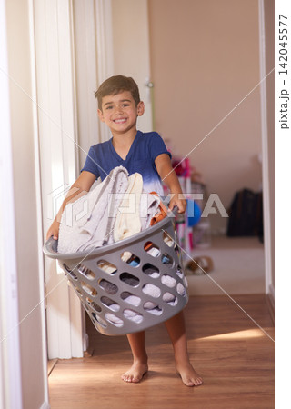 Laundry, smile and portrait of young child in home for chores, housework and learning responsibility. Washing basket, happiness and kid boy for routine, cleaning and housekeeping in apartment Laundry, smile and portrait of young child in home for chores, housework and learning responsibility. Washing basket, happiness and kid boy for routine, cleaning and housekeeping in apartment 142045577