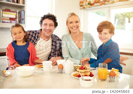 Family, portrait and breakfast in house kitchen for happy, pancakes and nutrition with plate, knife and fork. Dad, mother and kids in home at morning for love, brunch and health with fruit by table 142045603