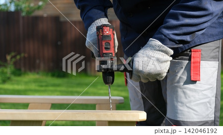 Builder worker using cordless hammer drill. Man with pneumatic perforator equipment making hole at construction. Installation process. Gloved hand grips the tool, precision and safety while working. 142046192