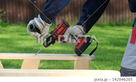 Builder worker using cordless hammer drill. Man with pneumatic perforator equipment making hole at construction. Installation process. Gloved hand grips the tool, precision and safety while working. 142046205
