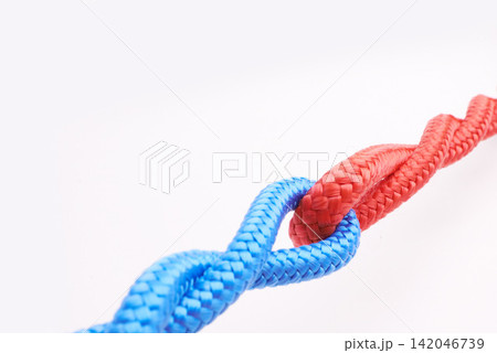 Rope, ties and connection with color in knot, link or loop together on white background in collaboration. Blue, red and join string in abstract unity with security from contact in chain or coil Rope, ties and connection with color in knot, link or loop together on white background in collaboration. Blue, red and join string in abstract unity with security from contact in chain or coil 142046739