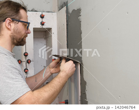 Worker Laying Ceramic Tiles on the Wall. Repairman Placing White Gray Square Tiles, Applying Adhesive. Builder Installing Tile Using Leveler, Tile Leveling Clips. Tiling. Finishing Repair Work. 4K Worker Laying Ceramic Tiles on the Wall. Repairman Placing White Gray Square Tiles, Applying Adhesive. Builder Installing Tile Using Leveler, Tile Leveling Clips. Tiling. Finishing Repair Work. 4K 142046764
