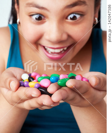 Girl, candy in hands and happy with snack for reward or bonus, shock or omg with winner of junk food. Sweets, jelly beans and excited kid for prize with joy, surprise or wow reaction with confection 142047386