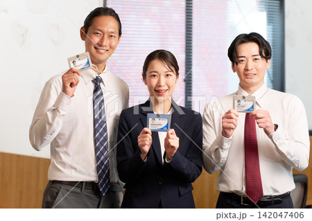 社員証を見せて笑顔で並ぶ3人のビジネスパーソン 社員証を見せて笑顔で並ぶ3人のビジネスパーソン 142047406