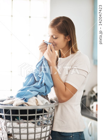 Laundry, fresh and woman smelling clothes after cleaning, housework and washing material in morning. Chores, housekeeping and cleaner or female person with basket, fabric or soft cotton in home 142047423
