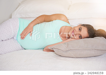 Portrait, bed and pregnant with woman, smile and relax with pillow, peaceful and wellness. Face, home and bedroom with girl, mother to be and apartment with happiness, pregnancy and stomach Portrait, bed and pregnant with woman, smile and relax with pillow, peaceful and wellness. Face, home and bedroom with girl, mother to be and apartment with happiness, pregnancy and stomach 142048159