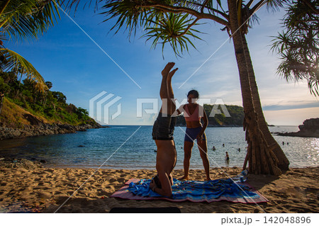 A man doing yoga in headstand pose on Yanui Beach. 142048896