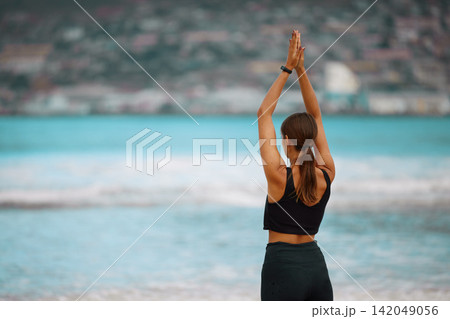 Exercise, meditation and yoga with woman on beach for awareness, balance or wellness in morning. Fitness, mindfulness and zen with back of person on sand by ocean for holistic training or workout Exercise, meditation and yoga with woman on beach for awareness, balance or wellness in morning. Fitness, mindfulness and zen with back of person on sand by ocean for holistic training or workout 142049056