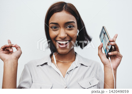 Phone, music and portrait of Indian girl with earphones in studio for dance, track or streaming audio on white background. Smartphone, app or gen z model smile for sign up playlist, radio or podcast Phone, music and portrait of Indian girl with earphones in studio for dance, track or streaming audio on white background. Smartphone, app or gen z model smile for sign up playlist, radio or podcast 142049059
