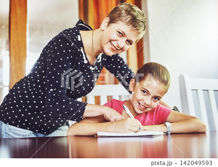 Mom, daughter and homework in portrait for learn with child development for education with writing, notebook and pen. Growth, study and homeschool at table with helping for assignment with paper 142049593