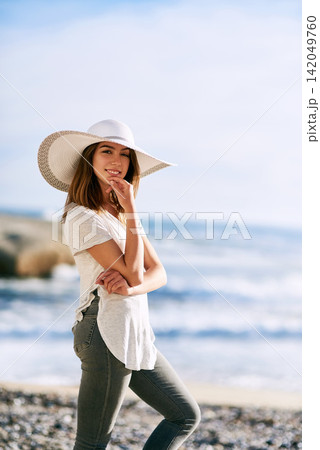 Confident, smile and portrait of woman at beach for summer vacation, holiday and adventure in Bali. Outdoor, tourist and relax by ocean on coast with hat for weekend trip, happiness and island travel 142049760