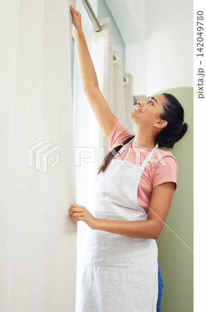 Woman, happy and hanging curtains in home for spring cleaning, housework or hygiene with diy. Housewife, person and window drapes in living room with smile, apron or housekeeping for domestic routine Woman, happy and hanging curtains in home for spring cleaning, housework or hygiene with diy. Housewife, person and window drapes in living room with smile, apron or housekeeping for domestic routine 142049780