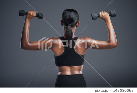 Woman, back and dumbbells in studio for arms, athlete for wellness and weight lifting exercise for power. Strong, Indian bodybuilder and health training, muscle and with equipment on background Woman, back and dumbbells in studio for arms, athlete for wellness and weight lifting exercise for power. Strong, Indian bodybuilder and health training, muscle and with equipment on background 142050068