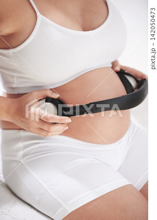 Mother, pregnant and headphones on stomach with music for calm stress relief, parent or listening. Person, audio and belly for soothing baby in womb for maternity bonding in home, technology or relax Mother, pregnant and headphones on stomach with music for calm stress relief, parent or listening. Person, audio and belly for soothing baby in womb for maternity bonding in home, technology or relax 142050473