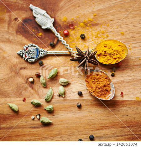 Spoons, spice and selection of seasoning for diet on kitchen table, turmeric and cardamom for meal. Top view, condiments and options for spicy gourmet in Indian culture, art and food preparation 142051074