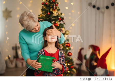 Grandmother surprising granddaughter with Christmas gift Grandmother surprising granddaughter with Christmas gift 142051513