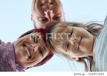 Family, portrait and sky for low angle, smile and hug in huddle for outdoor holiday. Parents, daughter and love for bonding and vacation in summer, mother and father for support and unity on getaway Family, portrait and sky for low angle, smile and hug in huddle for outdoor holiday. Parents, daughter and love for bonding and vacation in summer, mother and father for support and unity on getaway 142051691