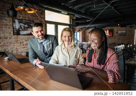 Diverse business people working together on a laptop in a cafe Diverse business people working together on a laptop in a cafe 142051952