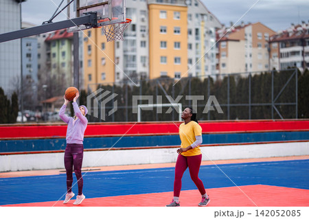 Two women playing basketball on urban outdoor court Two women playing basketball on urban outdoor court 142052085
