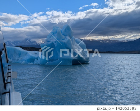 Blue Iceberg Beside Tour Boat on Patagonian Glacial Water Blue Iceberg Beside Tour Boat on Patagonian Glacial Water 142052595