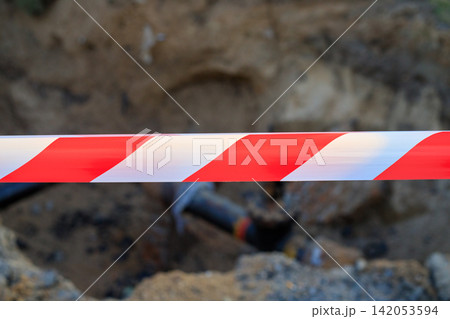 Red and White Warning Tape Stretched Across Utility Excavation Trench Red and White Warning Tape Stretched Across Utility Excavation Trench 142053594