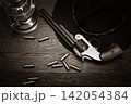 Antique Revolver with Ammunition, Cowboy Hat and Lantern on Wooden Table 142054384