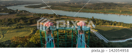Skywalk at Wat Phrathat Pha Ngao above the Mekong River landscape. The Buddhist temple and riverside setting reflect northern Thai heritage. Skywalk at Wat Phrathat Pha Ngao above the Mekong River landscape. The Buddhist temple and riverside setting reflect northern Thai heritage. 142054958
