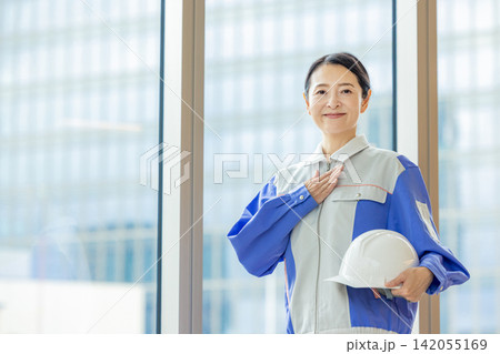 ヘルメットを持つ作業着の女性 ヘルメットを持つ作業着の女性 142055169