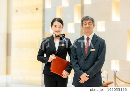 ホテルロビーに立つ支配人と女性スタッフ ホテルロビーに立つ支配人と女性スタッフ 142055186