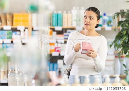 Middle-aged woman customer choosing needed pills in box in drugstore Middle-aged woman customer choosing needed pills in box in drugstore 142055798