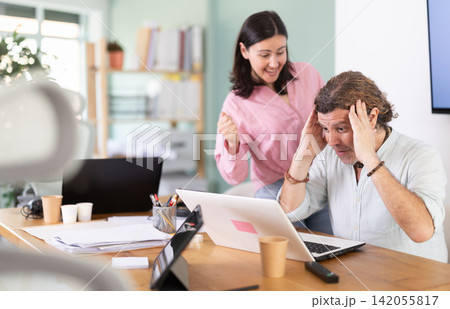 Happy male and female colleagues cheering at successful result on laptop 142055817