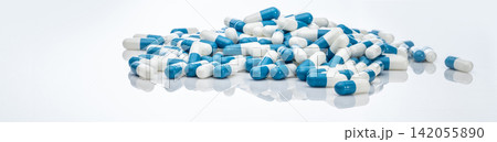 Blue-white antibiotic capsule pills on white background. Pile of antibiotic drug. Antibiotic drug resistance. Prescription drugs. Healthcare and medicine. Pharmaceutical industry. Pharmacy product. Blue-white antibiotic capsule pills on white background. Pile of antibiotic drug. Antibiotic drug resistance. Prescription drugs. Healthcare and medicine. Pharmaceutical industry. Pharmacy product. 142055890