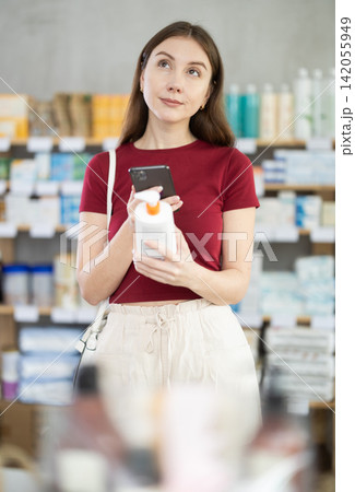 Woman in pharmacy scans QR code on cream Woman in pharmacy scans QR code on cream 142055949
