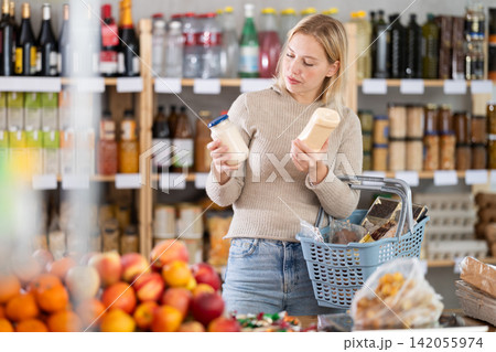 Young woman choosing mayonnaise in grocery store Young woman choosing mayonnaise in grocery store 142055974