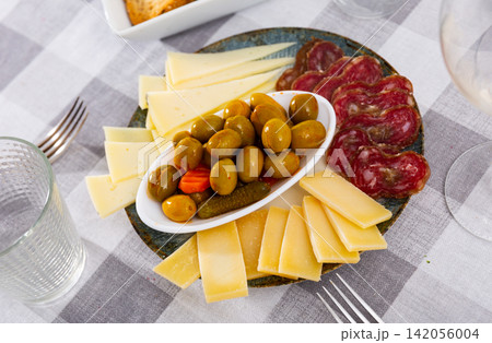 Snack plate - slicing several varieties of cheese, smoked sausage butifarra Snack plate - slicing several varieties of cheese, smoked sausage butifarra 142056004
