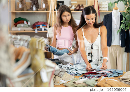 Mother and teenage daughter choosing jean shorts in clothing store Mother and teenage daughter choosing jean shorts in clothing store 142056005