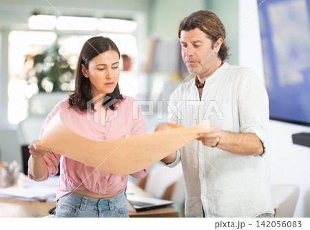 Middle-aged man and woman discussing construction plan standing in office Middle-aged man and woman discussing construction plan standing in office 142056083