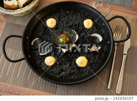 Paella is variant of dish made from black rice and seafood 142056107