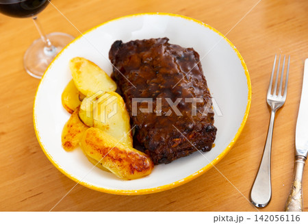 Pork ribs baked under sauce, served with potatoes Pork ribs baked under sauce, served with potatoes 142056116