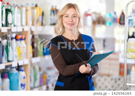 Charming young woman seller writing down care products and inventory in shop 142056165