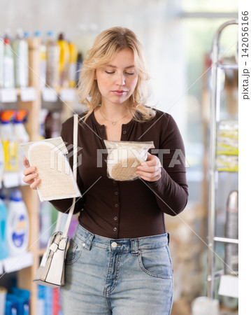 Positive young woman customer buying washcloth in store 142056166