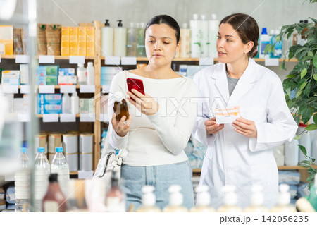 Young woman choosing herbal syrup in local pharmacy Young woman choosing herbal syrup in local pharmacy 142056235